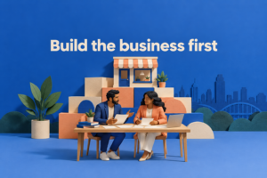 Conceptual AI-generated paper-sculpture scene of entrepreneurs planning a business, with the phrase Build the business first.